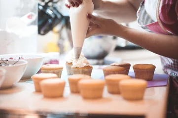 Foto op Plexiglas Woman making creamy top of cupcakes closeup. Selective focus. © morrowlight