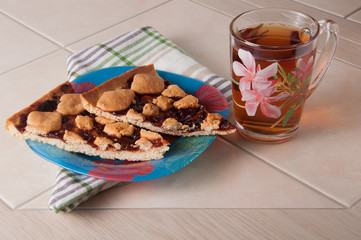 Cup of tea and plum cake with crumb on parchment paper