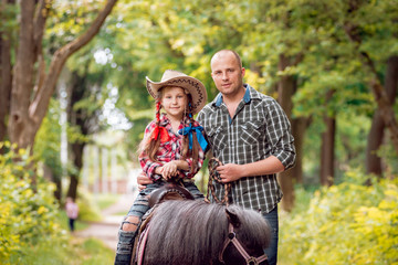 Beautiful little girl on a pony with his father.