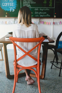 Young woman freelancer writing notes in cafe