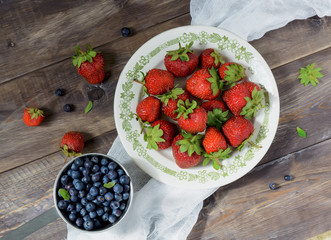 Blueberries and strawberries on a wooden table. Top view