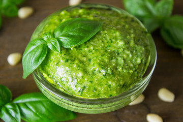 Homemade pesto sauce with ingredients over wooden table.