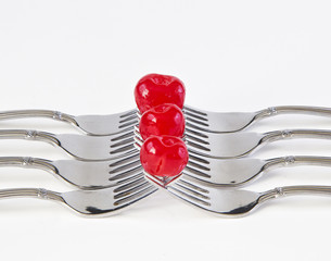 Three Cherries on forks with a white background