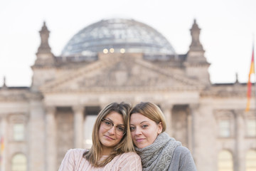 Portrait of two cute and blonde young women. In the background, out of focused Bundestag (Parliament building) of Berlin