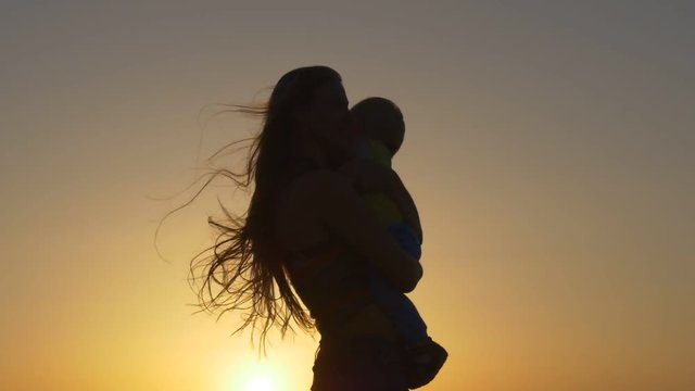 Silhouette of mother with her toddler against the sunset