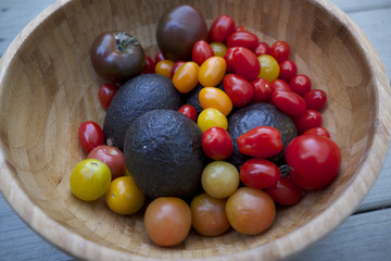 A bamboo bowl with mini heirloom tomatoes and avocados 