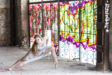 Dancer on pointe on background of the window brightly painted graffiti. Ballet, Classic, Modern, Contemporary