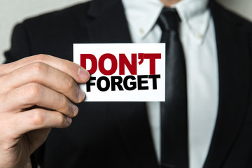 Business man holding a card with the text: Don't Forget
