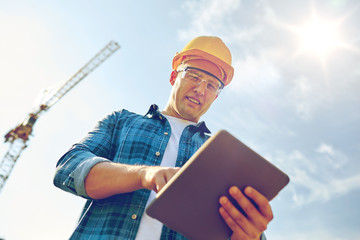 builder in hardhat with tablet pc at construction