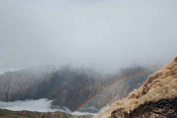 Rainbow in the mountains, peaks in the clouds