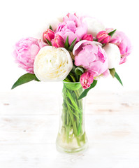 Summer bouquet of peonies in a glass vase on a white wooden tabl