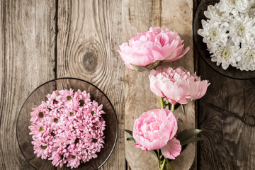 Peonies and plates with flowers on the wooden table top view
