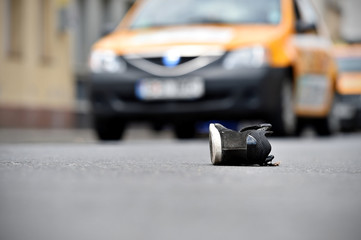 Shoe on the street with cars in background after accident
