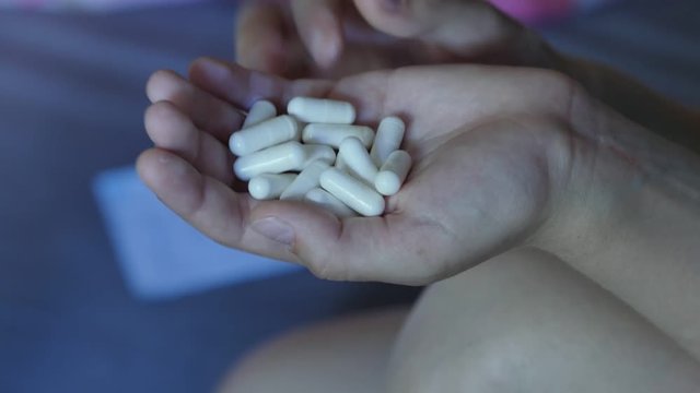 Desperate teen girl attempts to commit suicide with pills. 4K UHD.