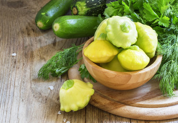 Yellow small pattypan in a bowl, vintage wooden background, sele