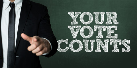 Business man pointing with the text: Your Vote Counts