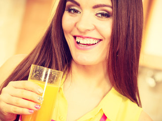 Woman in kitchen drinking fresh orange juice