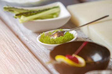 Green caviar in a bowl. Spoon in bowl with caviar. Fresh caviar for makizushi. Ingredient of an exquisite delicacy.