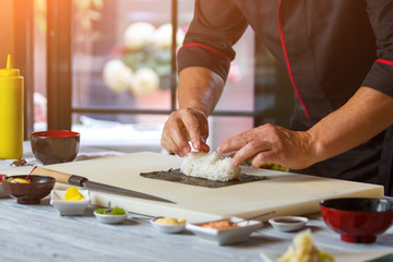 Nori and white rice. Man's hands touch rice. Chef starts cooking sushi. Simple recipe of hosomaki rolls.