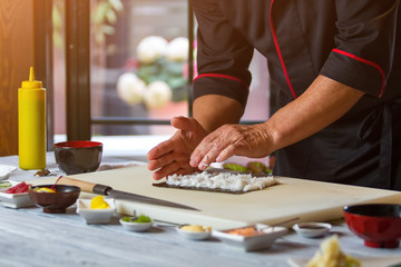 Obraz na płótnie Canvas Man's hands touch white rice. Rice on nori leaf. Japanese chef prepares sushi. Best ingredients for hosomaki rolls.