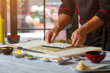 Male hands touching rice. Nori leaf with white rice. Chef's recipe of hosomaki rolls. Work in japanese restaurant's kitchen.