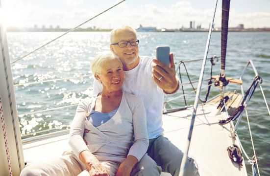 seniors with smartphone taking selfie on yacht