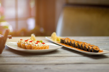 White plates with sushi rolls. Sauce and caviar on sushi. Choose what tastes better. Best recipes of japanese cuisine.