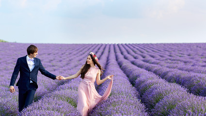 Wedding couple walking on a field of lavender, smiling, laughing