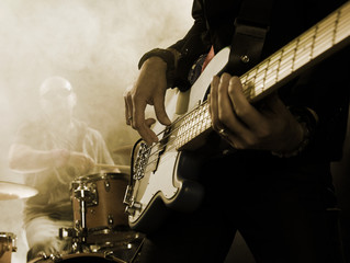 Rock band performs on stage. Bassist in the foreground. Close-up.