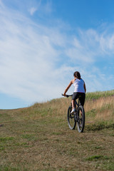 Fototapeta na wymiar Sport bike woman on the meadow with a beautiful landscape