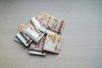 Stack of thousand bath Thai money on wooden table with copy space