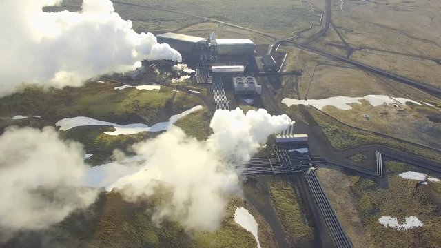 Aerial view of a geothermal power plant in Iceland. Steam rising upp against the sunlit sky from the plant