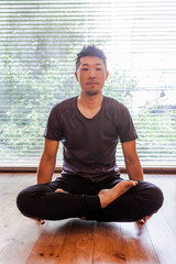 Fototapeta na wymiar Young Japanese man doing yoga, with legs drawn up, he remains suspended with the strength of arms