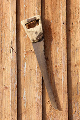 old retro tool/ old, rusty, the rural retro wood saw hanging on a nail 