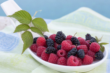 Berries in plates, on a table, among green leaves