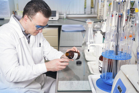 Laboratory assistant pours liquid from a bottle with sodium oxalate