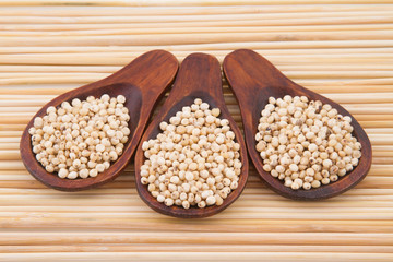 gluten free grains, millet, sorghum and linseed spoon on wooden natural background
