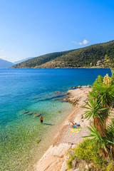 Unidentified couple of people relaxing on beach on coast of Kefalonia island in Agia Efimia, Greece