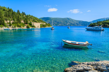 Fishing boat and yacht on turquoise sea in bay near Fiskardo village, Kefalonia island, Greece