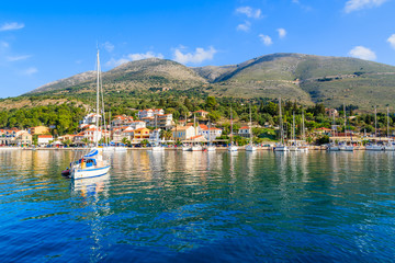 Yacht boat on blue sea and view of Agia Efimia fishing village with port, Kefalonia island, Greece
