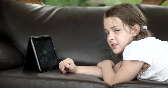 Girl Using Tablet Computer Lying on Leather Sofa on Terrace