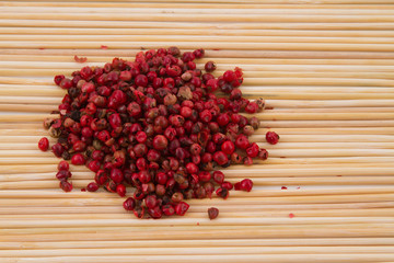 pink pepper with spoon and wooden background