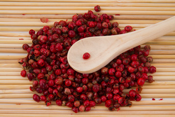 pink pepper with spoon and wooden background