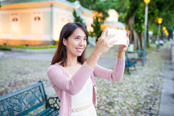Woman using cellphone to take photo in Macao city