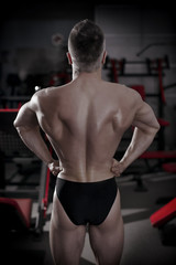 Fototapeta na wymiar Bodybuilder posing in gym. Perfect muscular male back