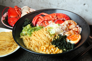 Traditional chinese bowl of wanton and vermicelli with shrimp, egg, corn and herbs on the table in restaurant