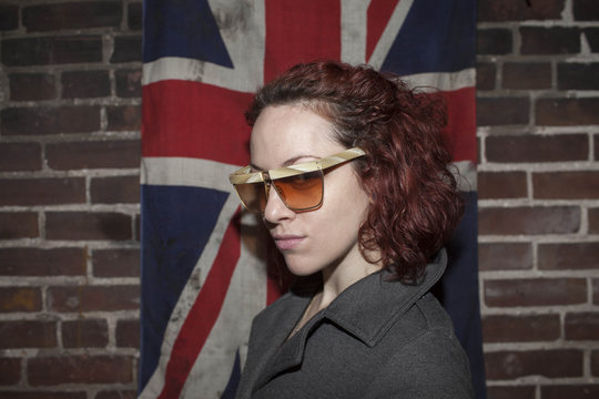 Portrait of young woman standing against British flag