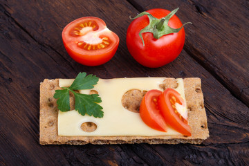 Crispy rye bread, cheese, tomato and parsley on an old table