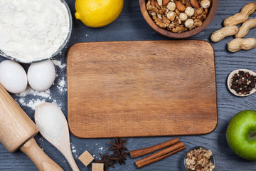 Ingredients for baking dough including flour, eggs, milk, whisk and rolling pin on wooden rustic background, empty space for text, top view
