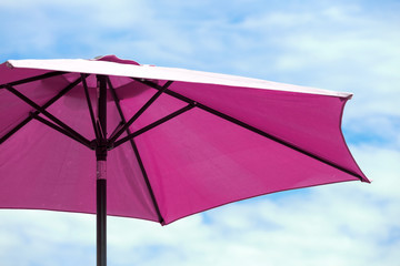 Dark pink parasol on blue coudy sky